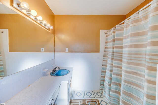 bathroom with tile walls, vanity, and walk in shower