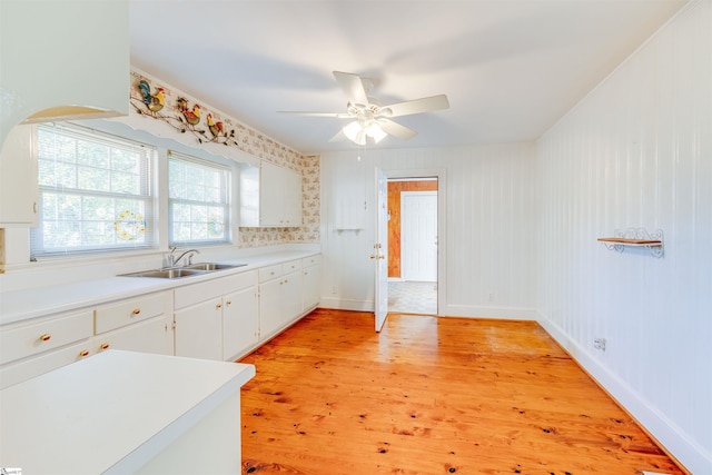 kitchen featuring light wood-type flooring, ceiling fan, sink, and white cabinets