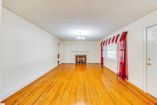 unfurnished living room with hardwood / wood-style floors, a fireplace, crown molding, an inviting chandelier, and a textured ceiling