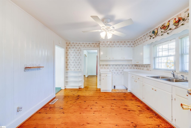 kitchen featuring ceiling fan, light hardwood / wood-style floors, sink, and white cabinetry