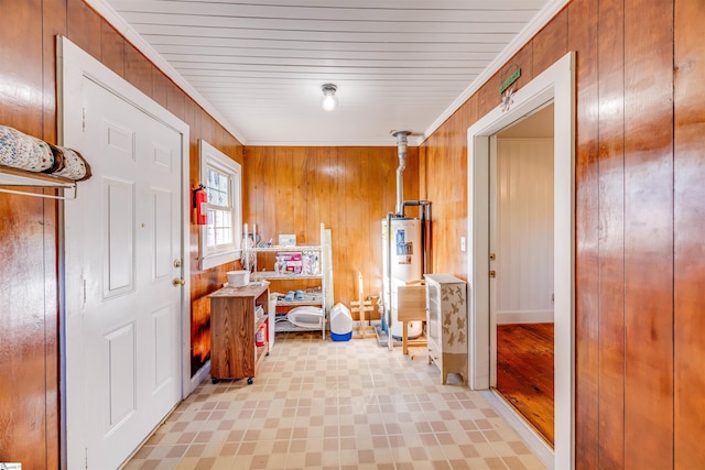 interior space featuring crown molding, water heater, and wooden walls