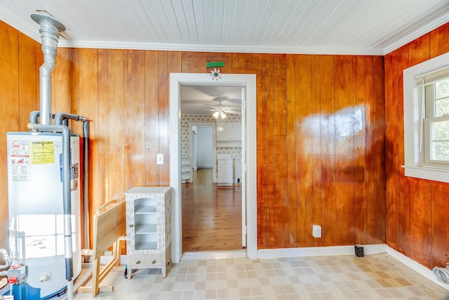 interior space with gas water heater, wooden walls, and ornamental molding