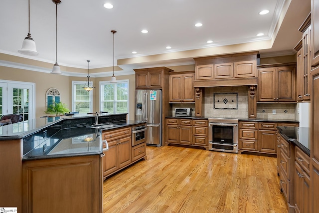 kitchen featuring pendant lighting, a kitchen island with sink, stainless steel appliances, and light wood-type flooring