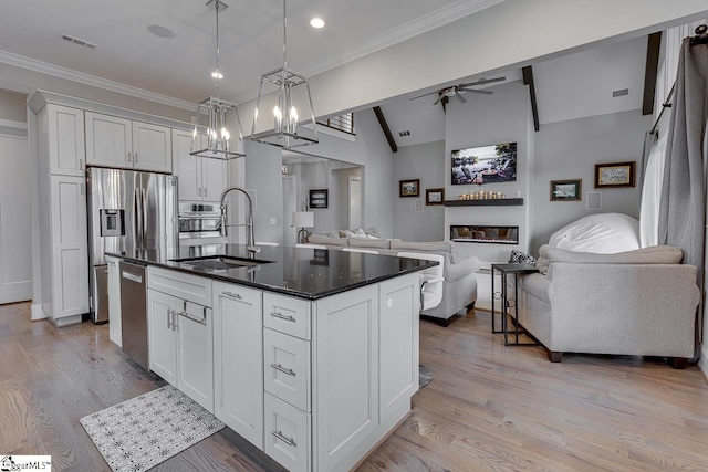 kitchen featuring a kitchen island with sink, sink, pendant lighting, white cabinetry, and light hardwood / wood-style flooring