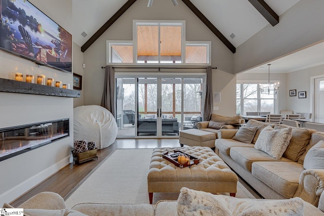 living room featuring light wood-type flooring, high vaulted ceiling, beam ceiling, and a chandelier