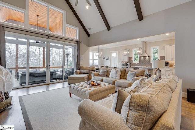 living room featuring an inviting chandelier, beam ceiling, light hardwood / wood-style flooring, sink, and high vaulted ceiling