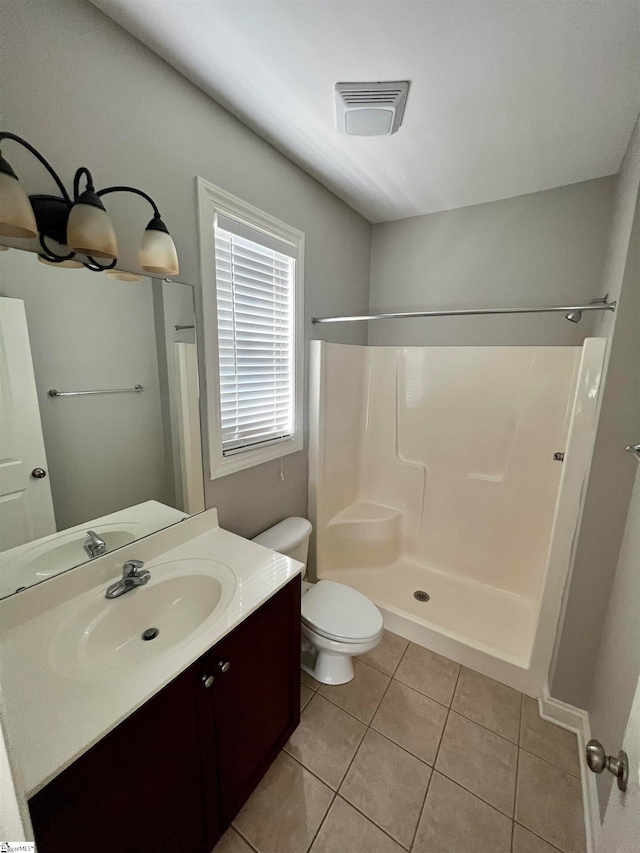 bathroom with tile patterned flooring, walk in shower, vanity, and toilet