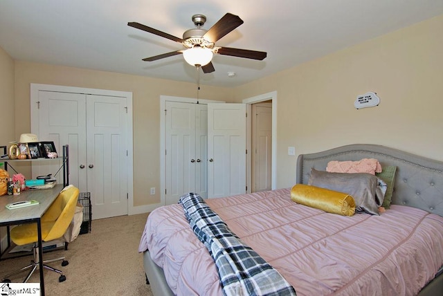 carpeted bedroom with ceiling fan and multiple closets