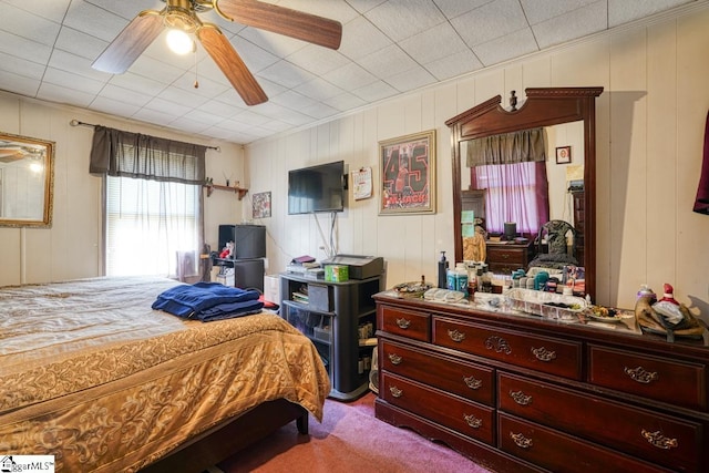 carpeted bedroom with wooden walls and ceiling fan