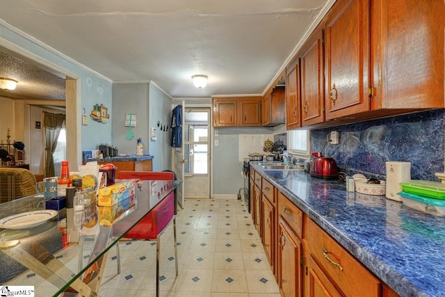 kitchen featuring ornamental molding, a breakfast bar area, sink, and dark stone countertops