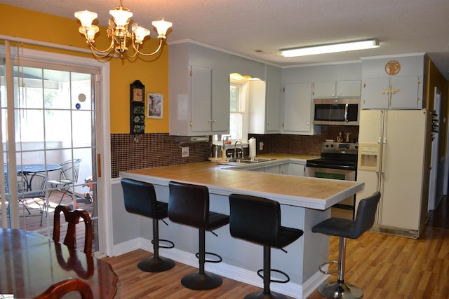 kitchen with pendant lighting, a breakfast bar area, sink, appliances with stainless steel finishes, and white cabinetry