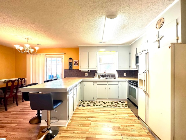 kitchen with light wood-type flooring, white refrigerator with ice dispenser, tasteful backsplash, kitchen peninsula, and black electric range