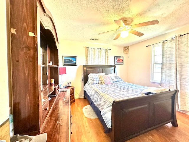 bedroom with ceiling fan, a textured ceiling, and light wood-type flooring