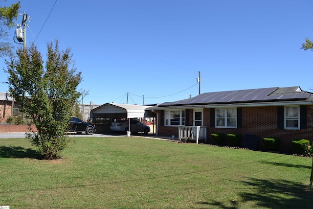 ranch-style house with solar panels, a carport, and a front yard