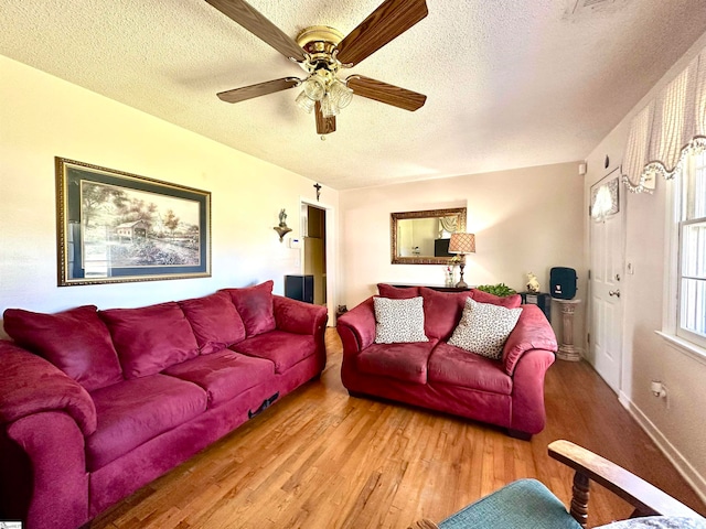 living room with hardwood / wood-style flooring, ceiling fan, and a textured ceiling