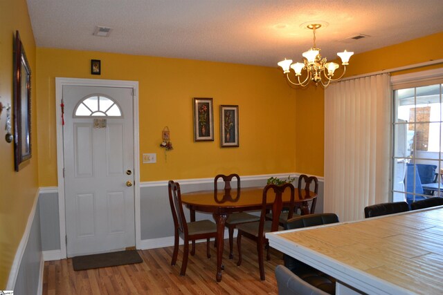 dining room featuring a textured ceiling, a chandelier, and hardwood / wood-style floors