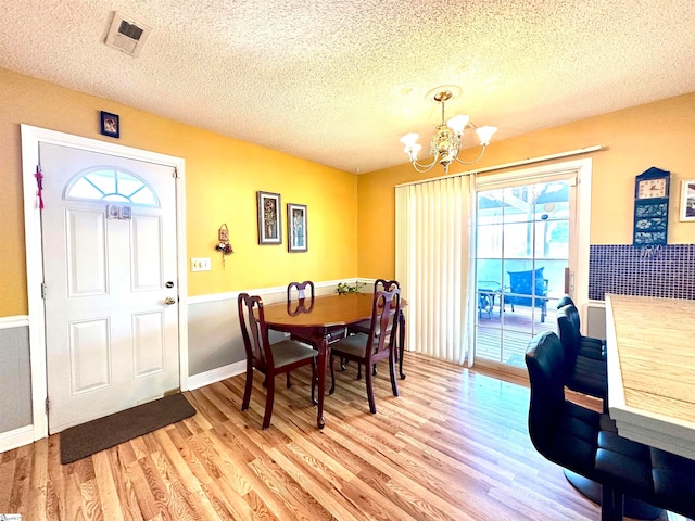 dining space with light wood-type flooring, a wealth of natural light, and a textured ceiling