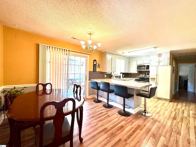 dining area featuring an inviting chandelier, sink, light hardwood / wood-style floors, and a textured ceiling