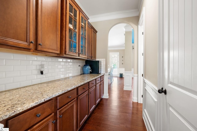 kitchen featuring tasteful backsplash, crown molding, light stone counters, and dark hardwood / wood-style flooring