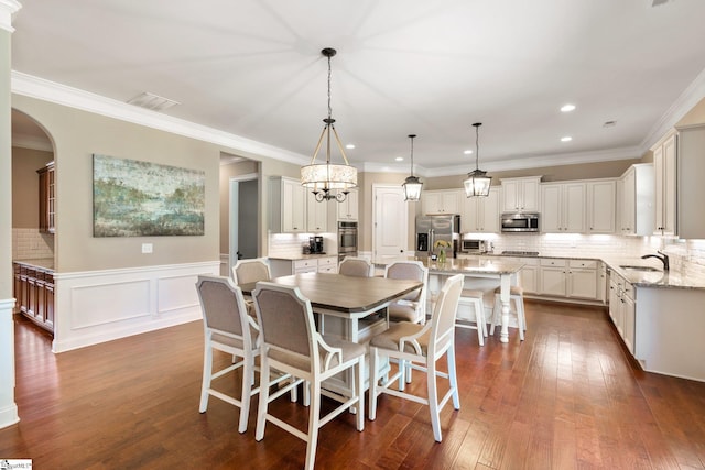 dining room featuring an inviting chandelier, dark hardwood / wood-style floors, sink, and ornamental molding