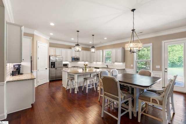 dining room with a healthy amount of sunlight, crown molding, sink, and dark hardwood / wood-style flooring