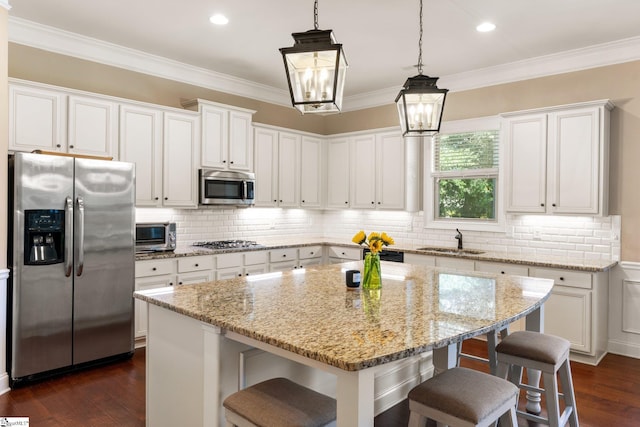 kitchen featuring appliances with stainless steel finishes, dark hardwood / wood-style flooring, a center island, and white cabinetry