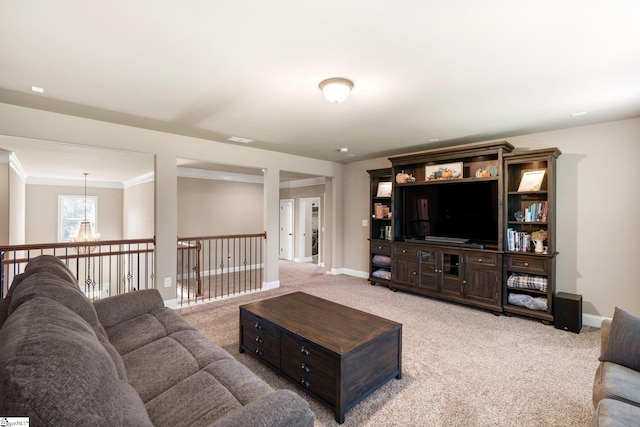 carpeted living room featuring ornamental molding and a chandelier