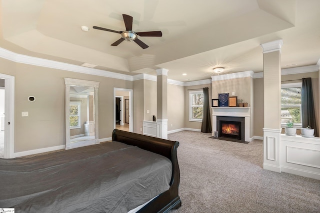 bedroom with a raised ceiling, light carpet, decorative columns, and ceiling fan