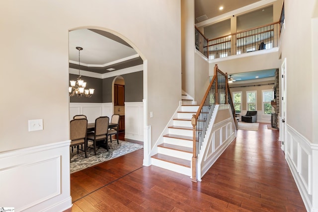 stairway with hardwood / wood-style flooring, crown molding, and a chandelier