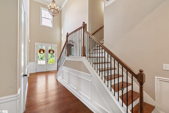 stairway with french doors, hardwood / wood-style flooring, crown molding, and a healthy amount of sunlight