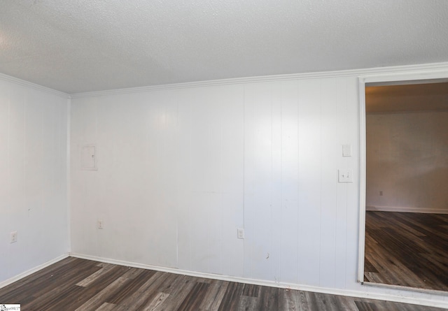 spare room featuring crown molding, a textured ceiling, wooden walls, and dark hardwood / wood-style floors