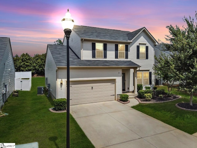 view of front of house featuring a garage, a yard, and central AC unit