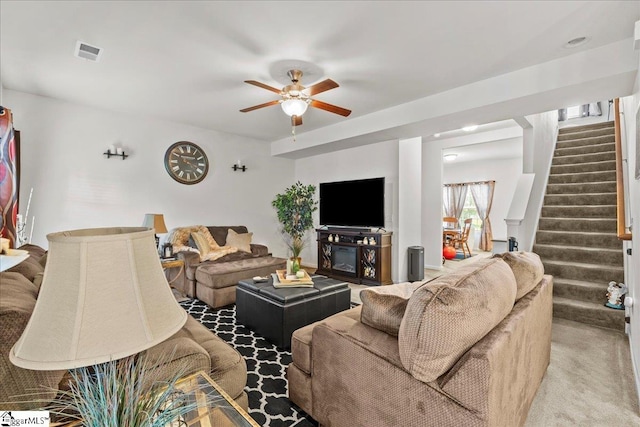 living room with a fireplace, ceiling fan, and carpet flooring