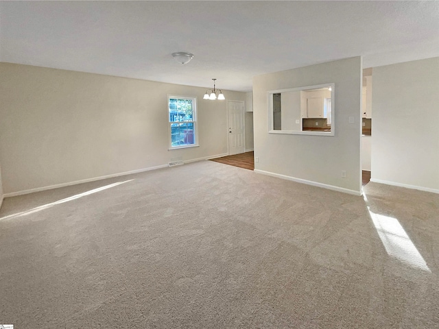 unfurnished living room featuring an inviting chandelier and carpet