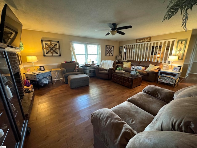 living room with ceiling fan, a textured ceiling, a brick fireplace, and dark hardwood / wood-style flooring