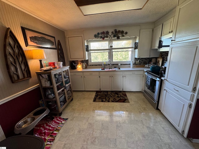 kitchen featuring appliances with stainless steel finishes, a textured ceiling, white cabinets, sink, and ornamental molding