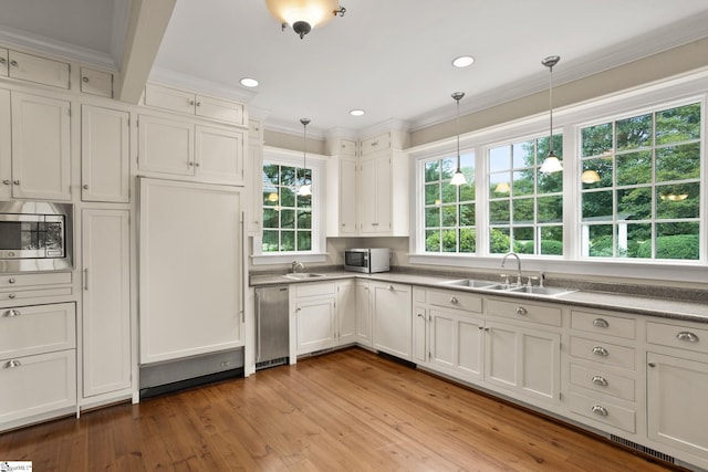 kitchen featuring appliances with stainless steel finishes, light wood-type flooring, and decorative light fixtures