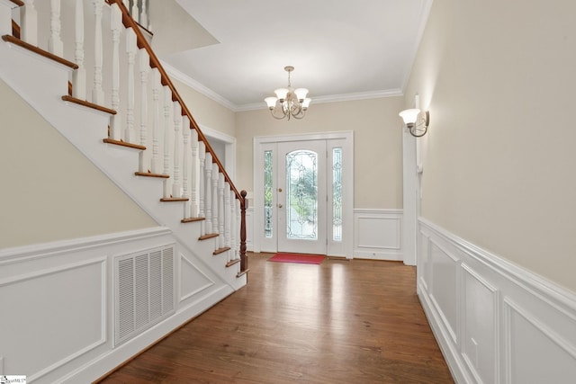 foyer entrance featuring crown molding, dark wood-type flooring, and a chandelier