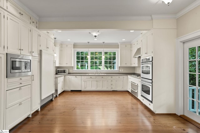 kitchen featuring light wood-type flooring, white cabinets, sink, ornamental molding, and built in appliances