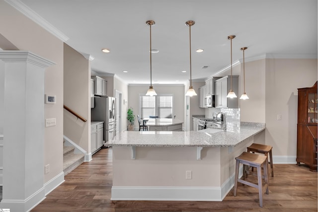 kitchen with pendant lighting, a kitchen bar, kitchen peninsula, and stainless steel appliances