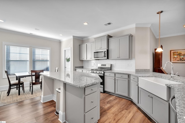 kitchen with stainless steel appliances, light hardwood / wood-style floors, gray cabinets, and decorative light fixtures