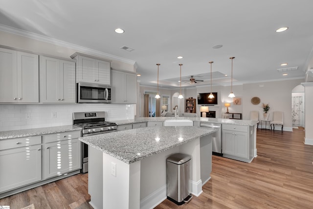 kitchen with ceiling fan, stainless steel appliances, light hardwood / wood-style floors, kitchen peninsula, and hanging light fixtures