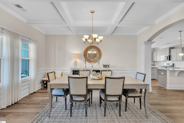 dining area featuring ornamental molding, a notable chandelier, coffered ceiling, and light hardwood / wood-style floors