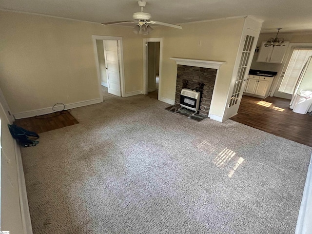 unfurnished living room featuring heating unit, ceiling fan with notable chandelier, and dark hardwood / wood-style flooring