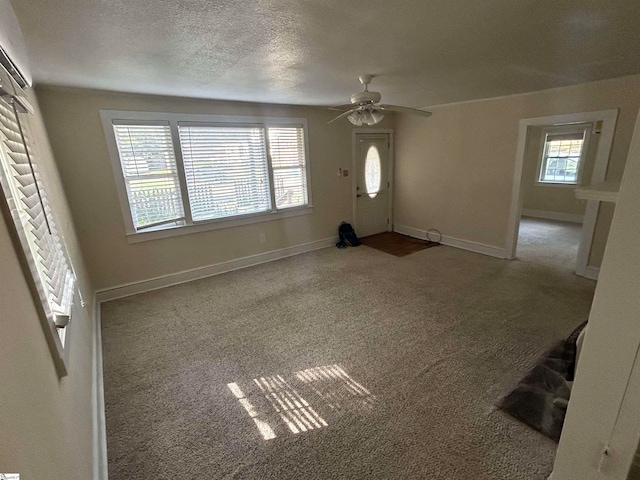 foyer featuring ceiling fan, a textured ceiling, carpet, and a wealth of natural light