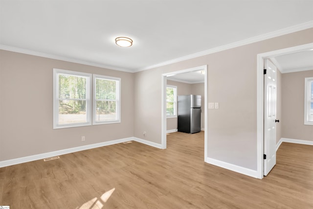 spare room featuring light wood-type flooring and ornamental molding