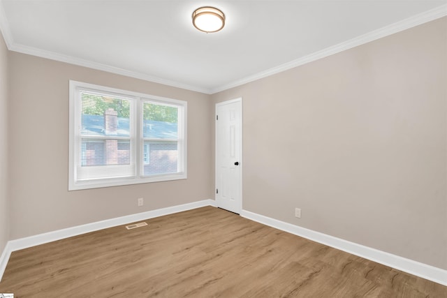 spare room featuring ornamental molding and light hardwood / wood-style flooring