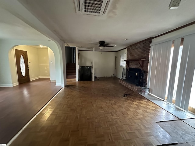 unfurnished living room featuring a brick fireplace and ceiling fan