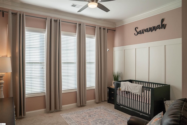 carpeted bedroom with crown molding, multiple windows, and a crib