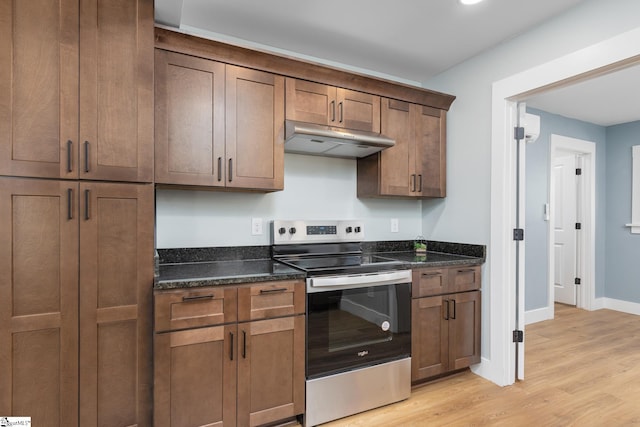 kitchen featuring dark stone countertops, light hardwood / wood-style flooring, and electric range